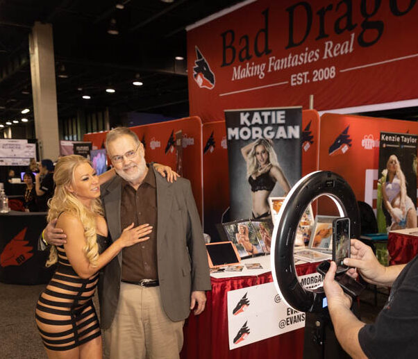 Performer posing with a fan for a photo at EXXXOTICA booth during Saturday appearance
