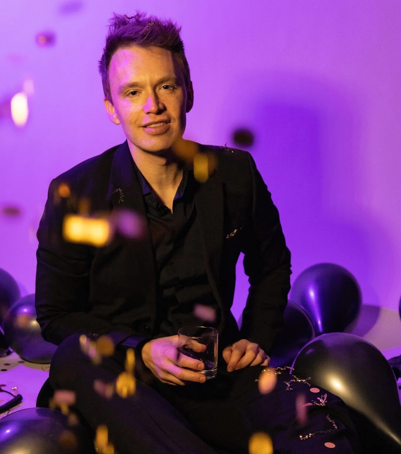Dustin Rybka seated in a dark suit under purple lighting
